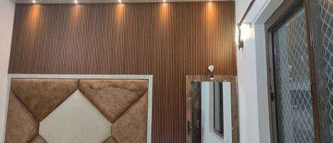 A room with a wooden panel wall, a geometric patterned door, and a glass door with a diamond pattern.