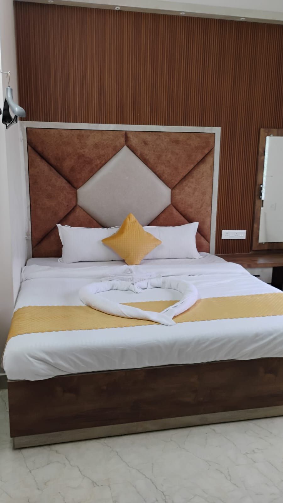 A neatly made bed with a geometric headboard, white bedding, and a yellow pillow.