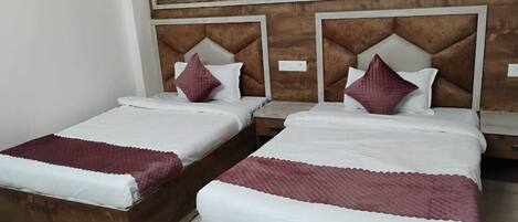 Two single beds with wooden headboards and white bedding, a wooden nightstand, and a large painting on the wall.