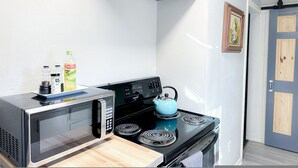 Una cocina compacta con microondas, estufa y hervidor.