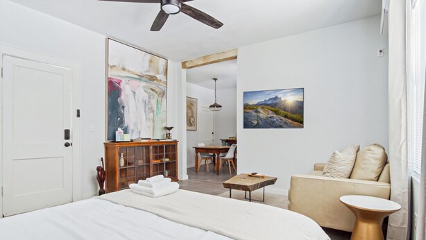 A modern bedroom with a large bed, a wooden cabinet, a dining area, and a sofa. - Adorned Studio 3min-asian Dist Rain Shower (Oklahoma City)