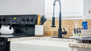 A kitchen with a stove, a kettle, a coffee maker, and a sink. - Adorned Studio 3min-asian Dist Rain Shower (Oklahoma City)