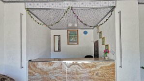 A reception area with a marble counter, a clock, framed pictures, and a decorative garland on the ceiling. - Hotel O Majest (Bontang)