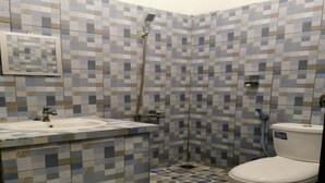 A bathroom with a tiled shower, a sink, and a toilet. - Hotel O Majest (Bontang)