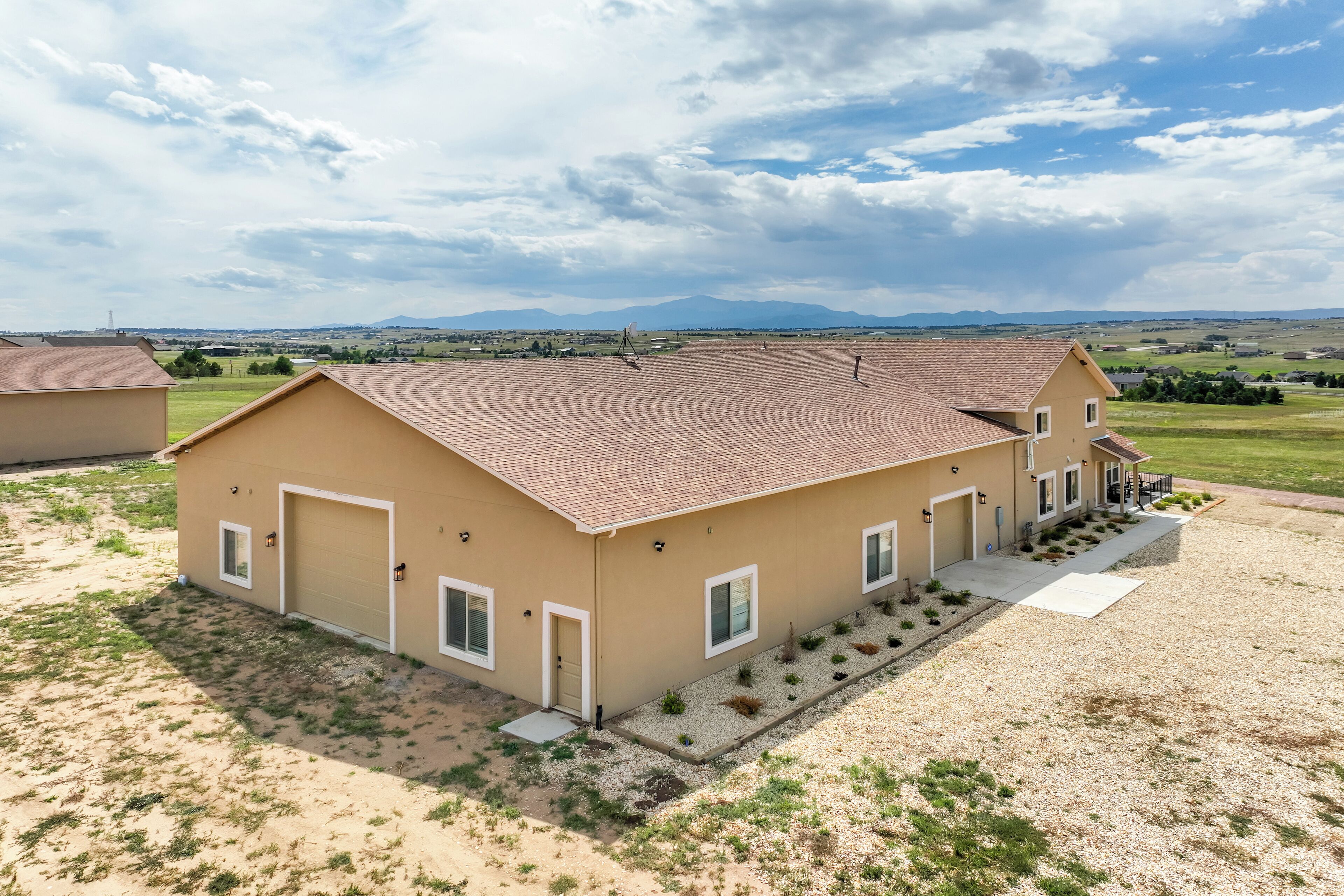 A two-story house with a tiled roof, a front porch, and a driveway.