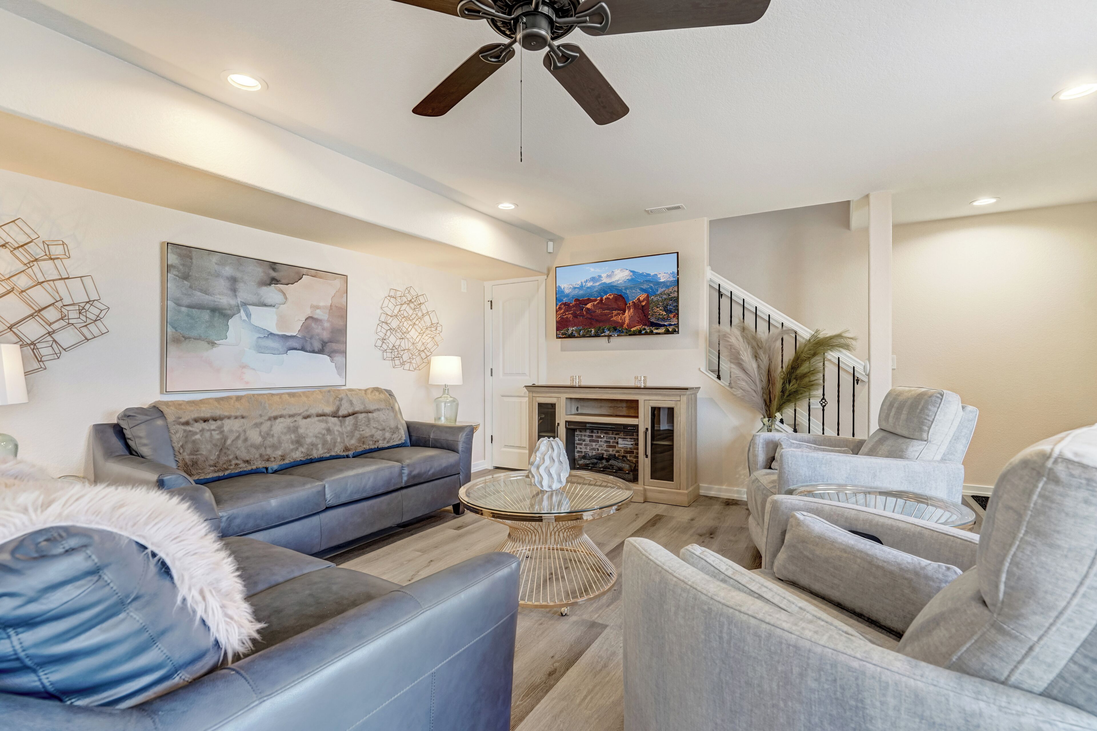 A modern living room with a grey sofa, a round glass coffee table, and a fireplace.