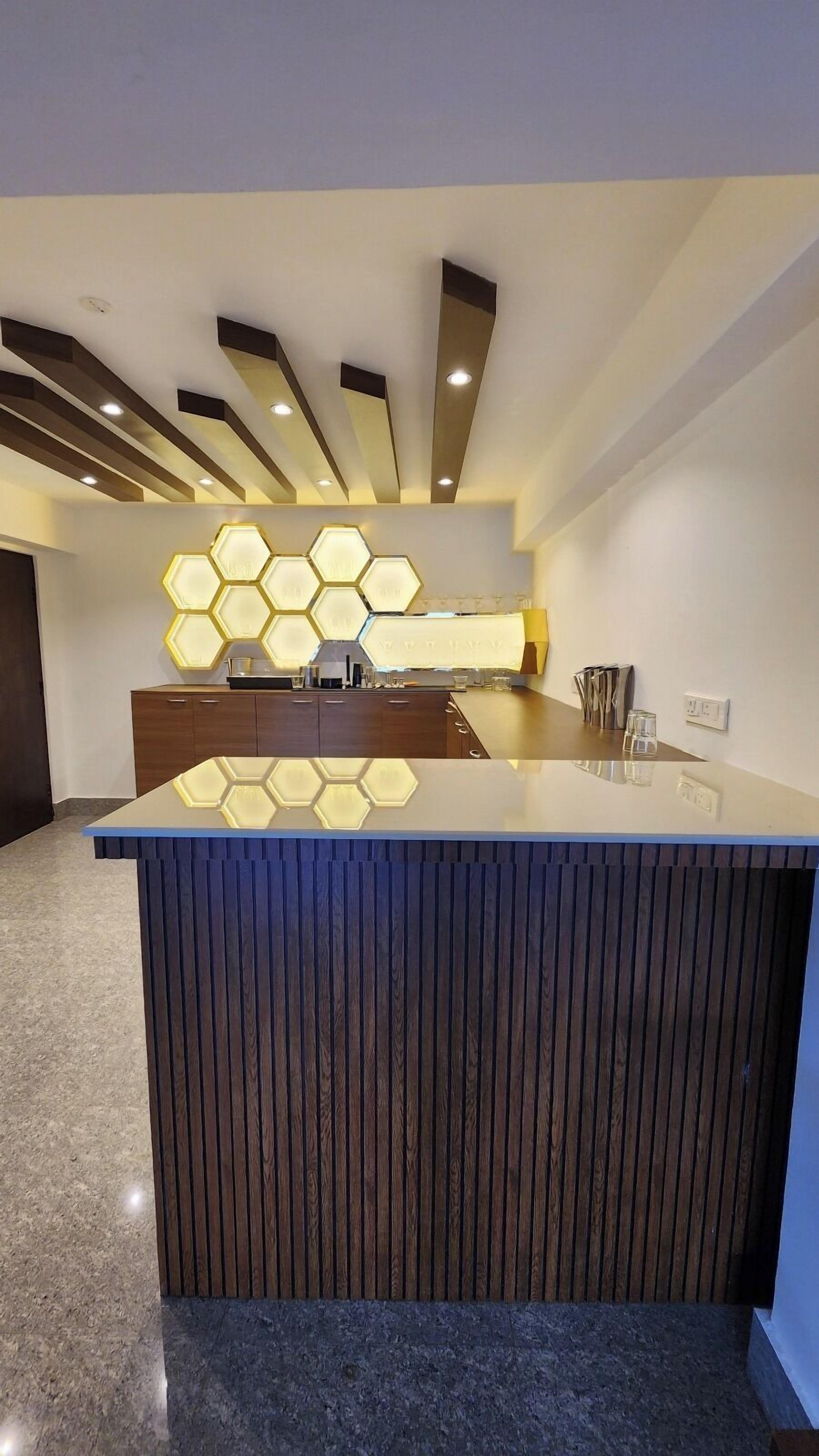 A modern reception desk with a geometric light fixture above and a wooden panel design.