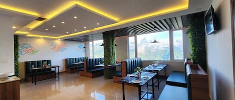 A modern dining area with booths and tables, large windows, and decorative wall art.