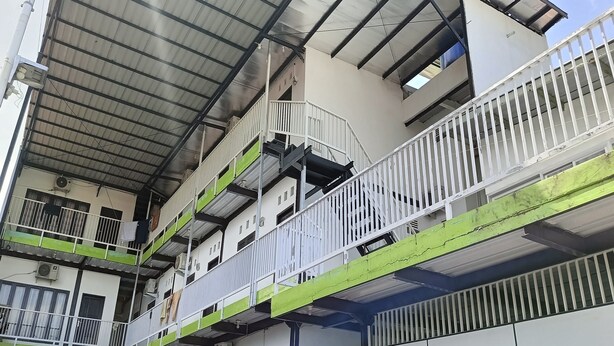 Un edificio de varios pisos con balcones, barandillas y techo metálico.