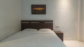 Un dormitorio con cama, mesita de noche y un cuadro en la pared.