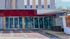 A modern building with a flat roof, large windows, and a red awning. - Hotel O Sman House (Bekasi)