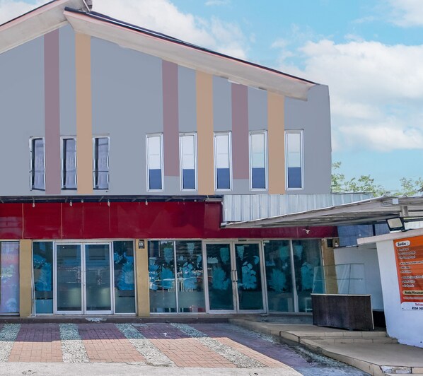 Egy modern épület, lapos tetővel, nagy ablakokkal és piros színű napellenzővel.