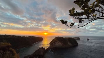 A coastal landscape with a sunset, rocky formations, and a river.