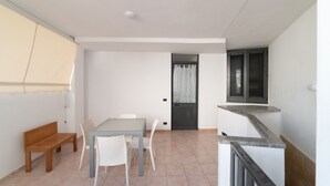Una habitación con una mesa de comedor, sillas, un banco, una escalera y una puerta con cortina.