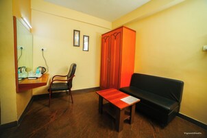 Una habitación con una mesa de madera, un sofá negro, una silla de madera y un armario rojo.