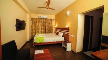 A hotel room with a bed, bedside table, nightstand, and a ceiling fan.