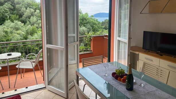 A balcony with a table set for two, a TV, and a bottle of champagne. - Green Oasis 1 (Lerici)