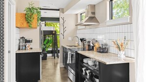 A modern kitchen with black cabinets, white subway tiles, and a granite countertop. - Modern Home with Rooftop Deck - Walk to Coffee, Restaurants, Brewery (Nashville)