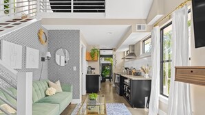 A modern interior with a green sofa, a glass coffee table, and a kitchen area with a dining table. - Modern Home with Rooftop Deck - Walk to Coffee, Restaurants, Brewery (Nashville)