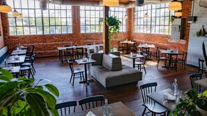 A restaurant with brick walls, large windows, wooden floors, and a mix of tables and seating areas. - Modern Home with Rooftop Deck - Walk to Coffee, Restaurants, Brewery (Nashville)