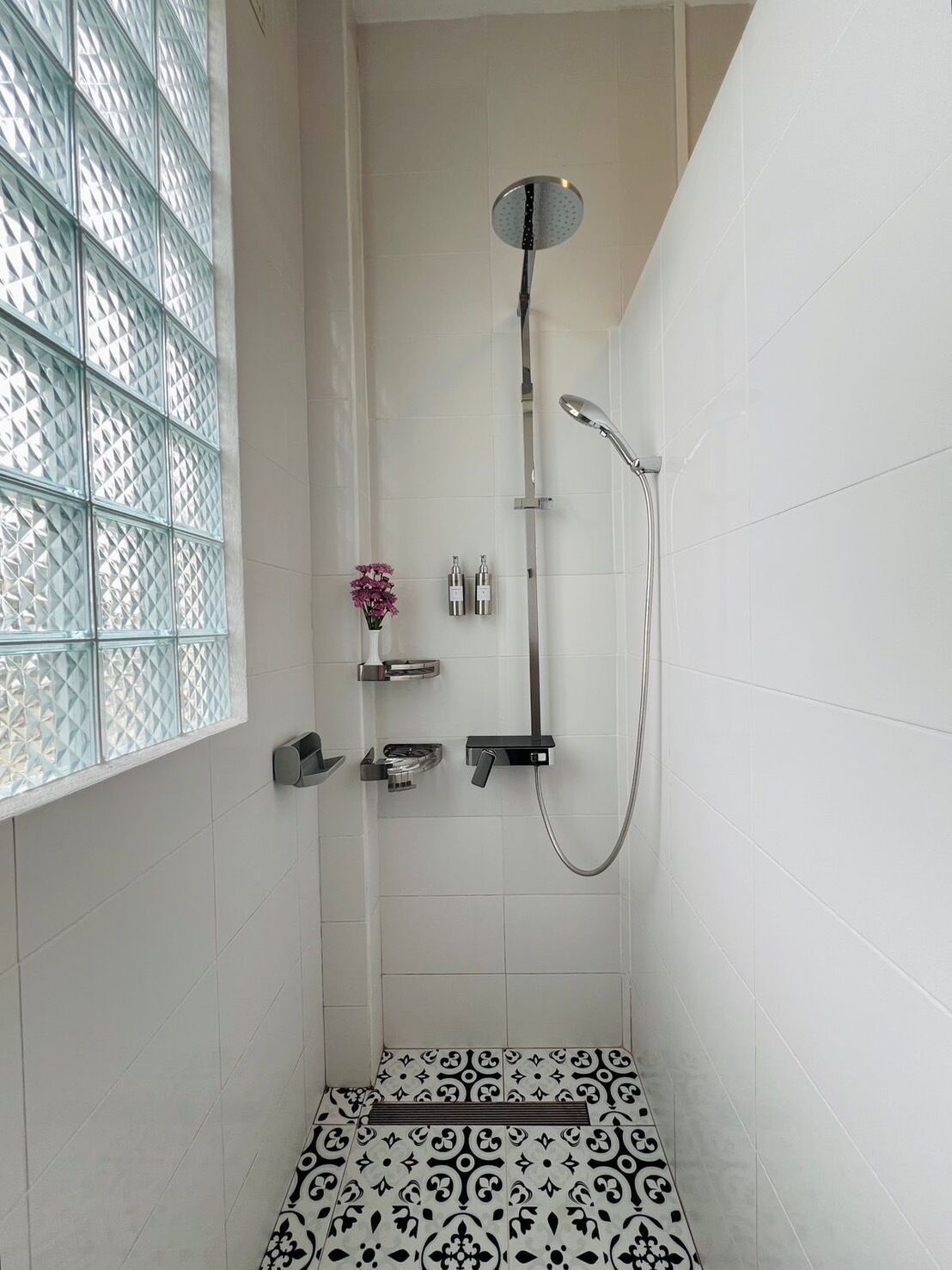 A modern shower with a glass partition, a handheld showerhead, and a wall-mounted faucet.