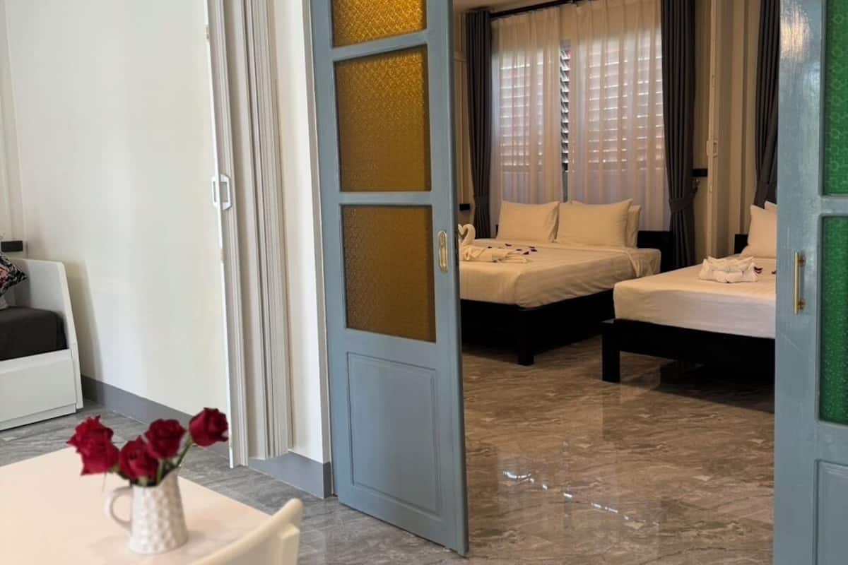 A hotel room with a bed, a desk, and a chair. There is a vase with flowers on the desk.