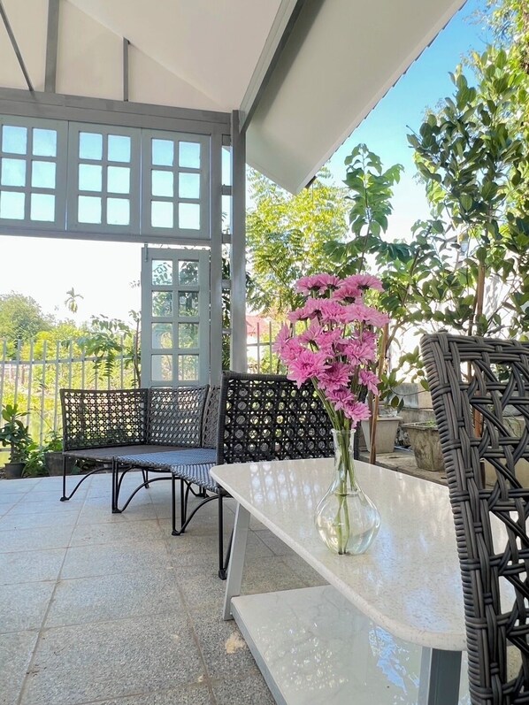 Une terrasse extérieure avec une table blanche et deux chaises en osier noir.