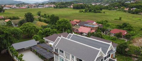 Un grand immeuble à étages, doté d’une architecture moderne, entouré de vastes prairies verdoyantes et bordé par une rivière.