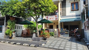 Un restaurant avec une terrasse, une moto garée devant et une enseigne publicitaire annonçant les plats proposés.