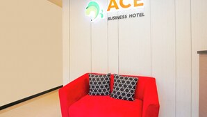 A red sofa with patterned cushions in front of a wall with a logo and text reading "ACE BUSINESS HOTEL". - Hotel O Rungkut Near Its Surabaya Formerly Ace Business Hotel (Surabaya)