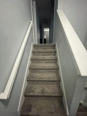A staircase with carpeted steps and white handrails, leading to a door at the top. - Charming 4-bedroom house with AC and WiFi in lovely Indianapolis (Indianapolis)