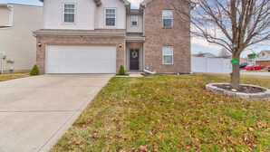 A two-story residential house with a garage, a front yard with a tree, and a clear sky. - Charming 4-bedroom house with AC and WiFi in lovely Indianapolis (Indianapolis)
