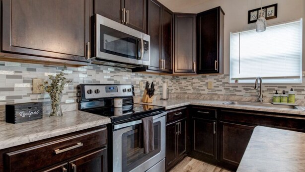 A kitchen with dark wood cabinets, stainless steel appliances, a tiled backsplash, and a window with blinds. - Charming 4-bedroom house with AC and WiFi in lovely Indianapolis (Indianapolis)