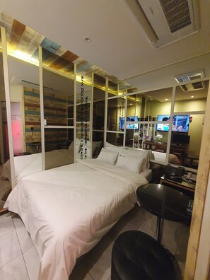 A modern hotel room with a large bed, a small desk, and multiple screens on the wall. - Eunpyeong Y HOTEL (Seoul)
