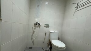 Ein kleines Badezimmer mit Fliesen, einer Toilette, einer Dusche und einem Händetrockner.