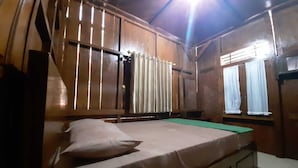 Ein Zimmer mit Holzboden, einem Bett, Vorhängen und einem Fenster.
