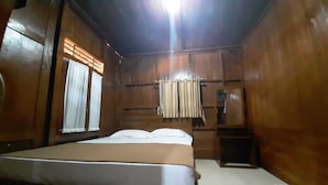 Ein Zimmer aus Holz mit einem Bett, einem kleinen Tisch und einem Regal.