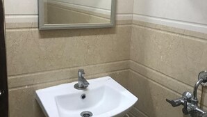 Een badkamer met een wit wastafel, een spiegel en een douche.
