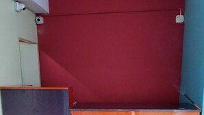 Een kamer met een rode en oranje wand, een paars paneel en een wit kastje.