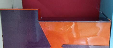 A room with a red and orange wall, a purple panel, and a white cabinet.