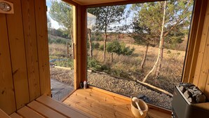 A wooden cabin with a large window offering a view of a forested landscape.