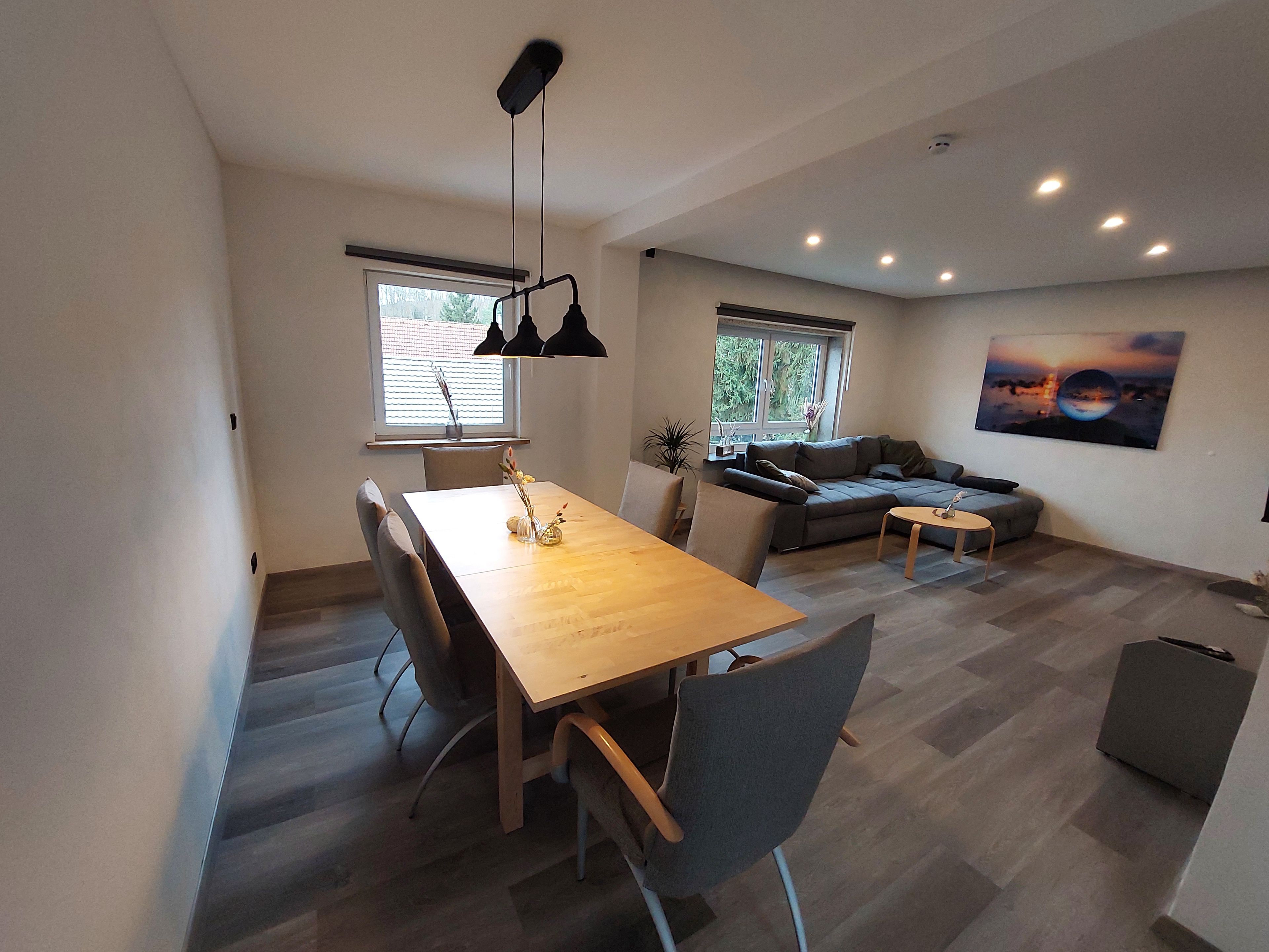 A modern living space with a dining area, sofa, and artwork.