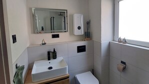 Une salle de bain moderne avec un lavabo blanc, un meuble-lavabo en bois, des toilettes et un miroir.