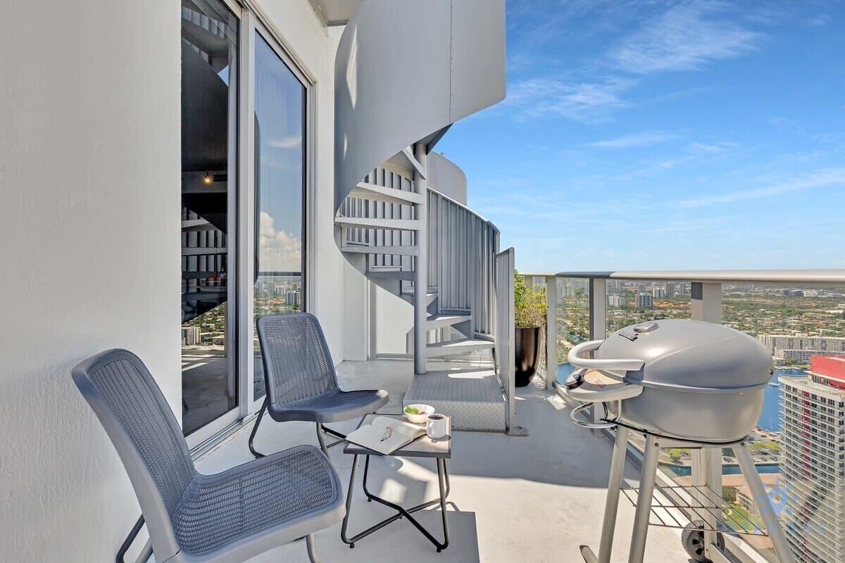 A balcony with two chairs, a small table, and a grill.