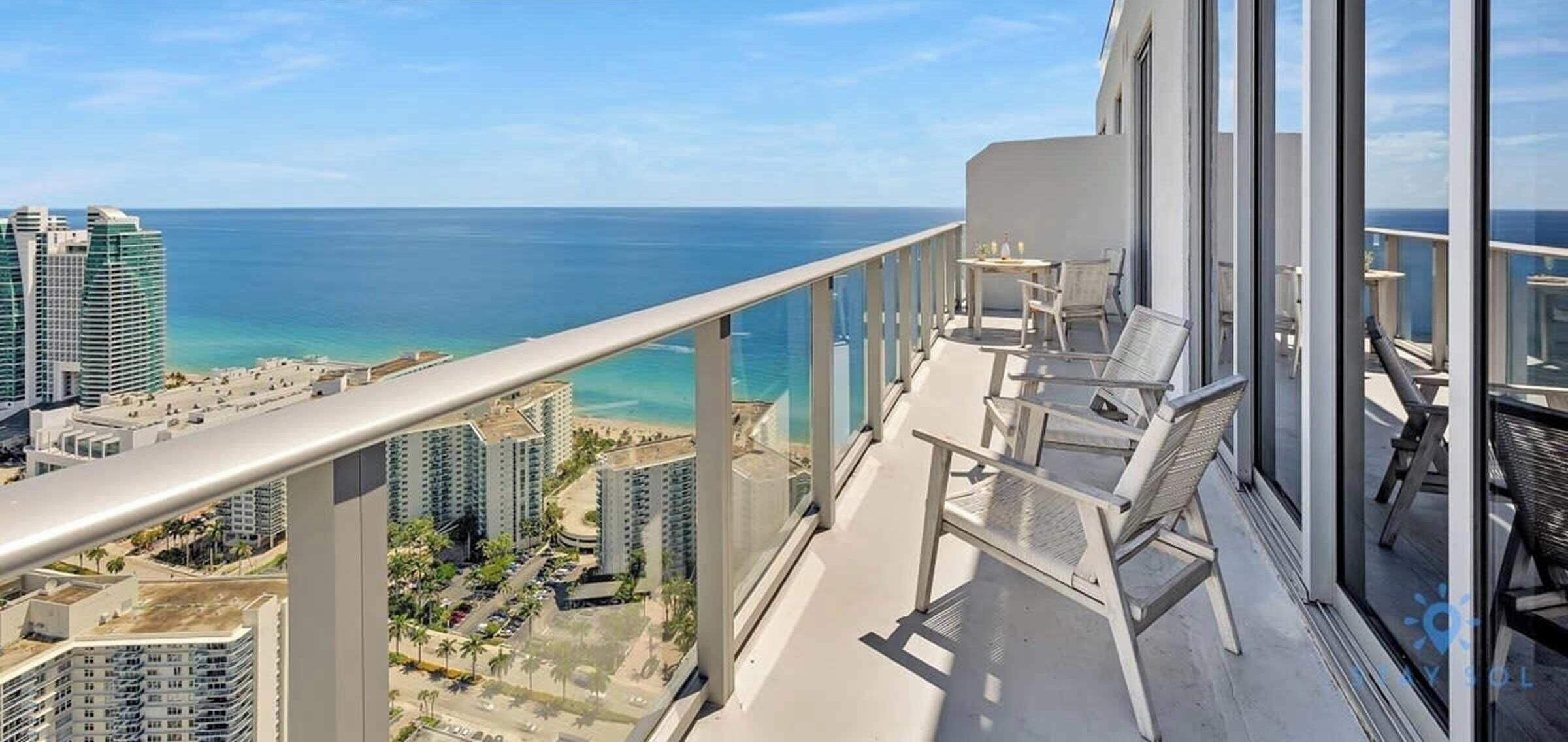 A balcony with a view of the ocean and cityscape.