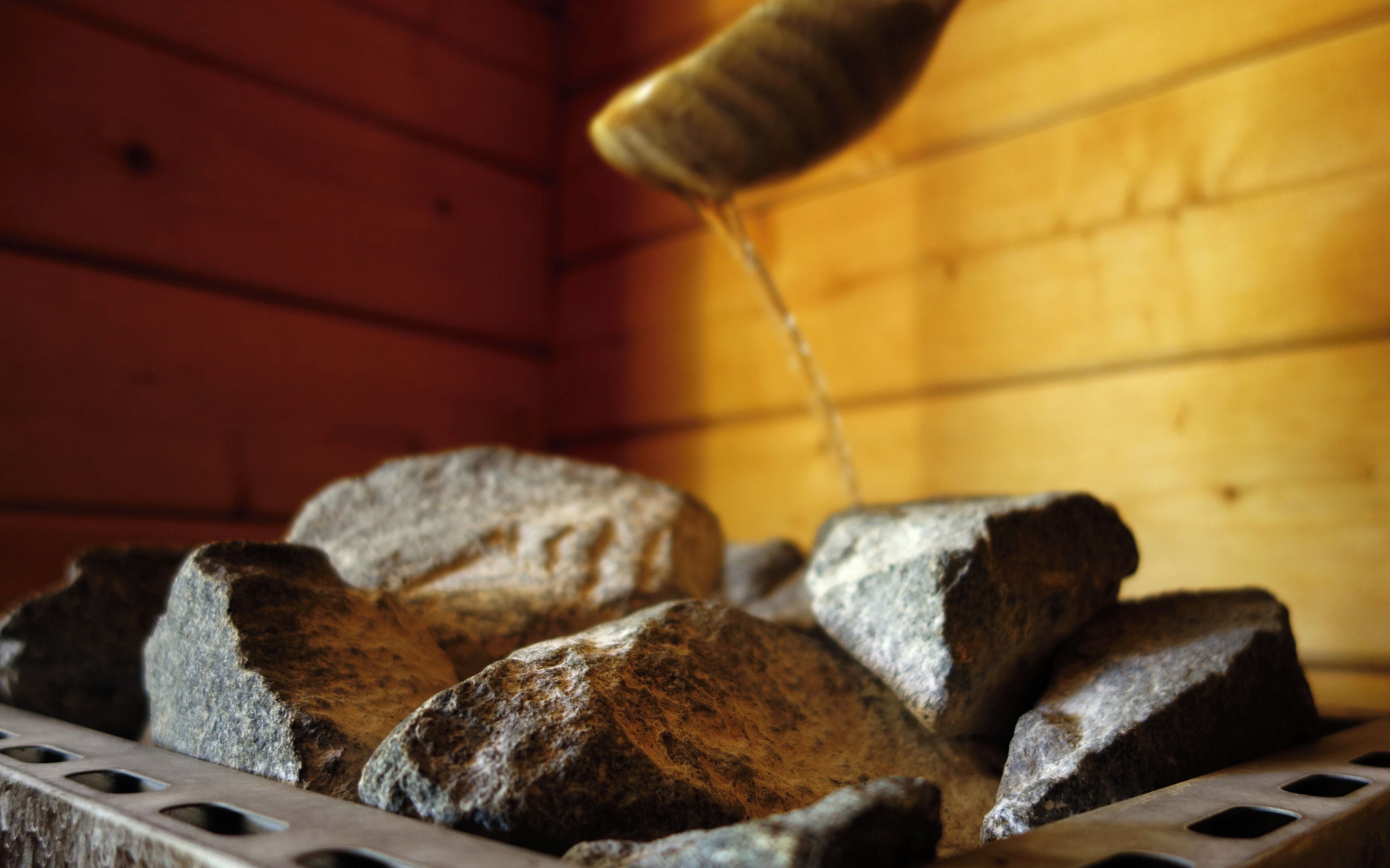 A close-up of a wooden log cabin interior with a focus on a metal grate and several logs.
