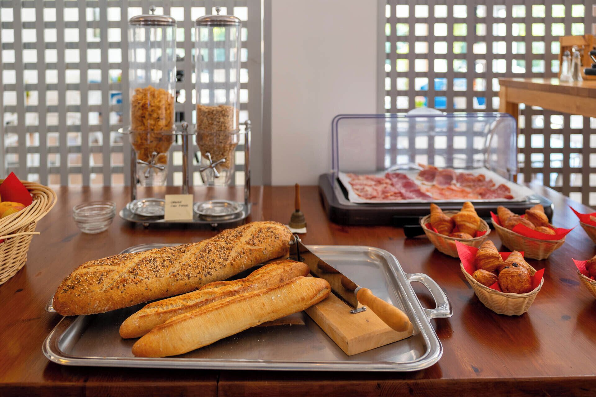 Un bufé de desayuno con panes, bollería y embutidos variados.
