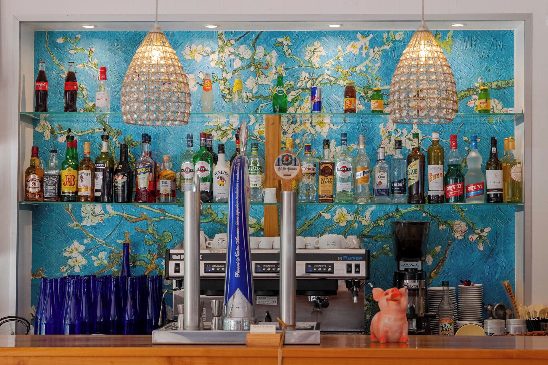 A bar area with a variety of liquor bottles, a coffee machine, and a decorative pig statue.