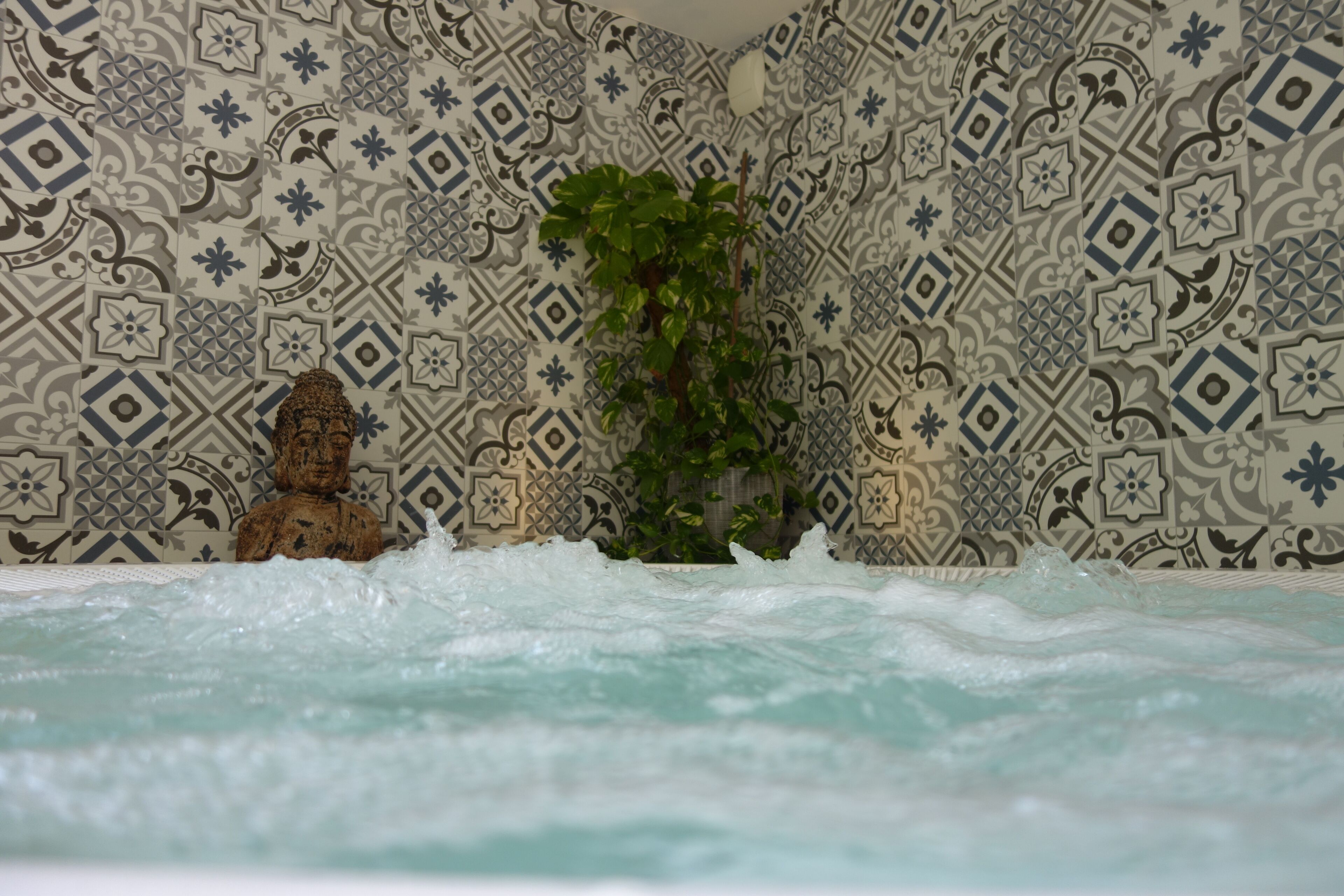 Una vasca da bagno con una parete decorata da elaborate decorazioni in piastrelle.