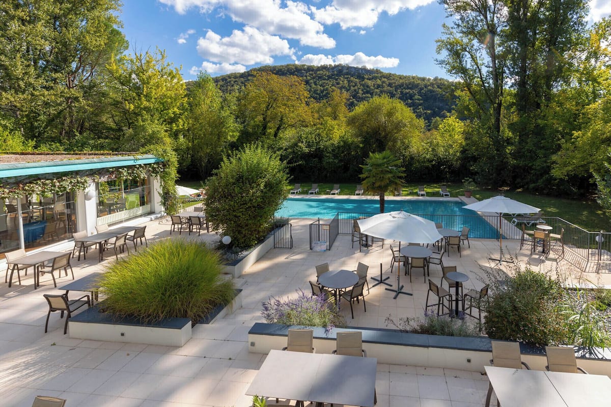 An outdoor patio area with a pool, surrounded by lush greenery and trees.